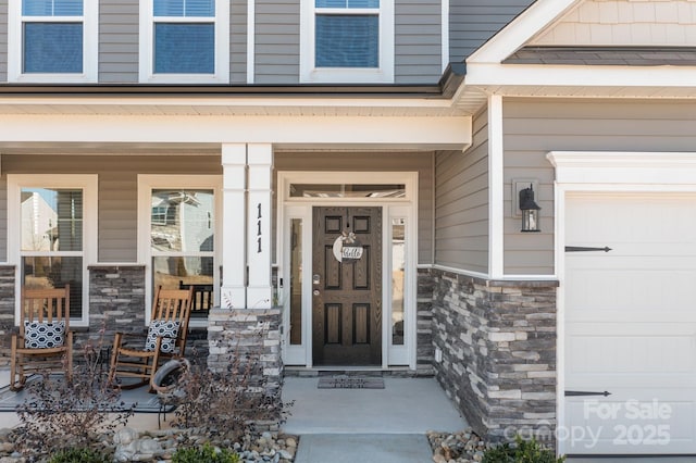 view of exterior entry featuring a garage and stone siding