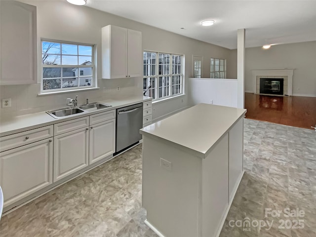 kitchen featuring dishwasher, a kitchen island, a sink, and white cabinetry