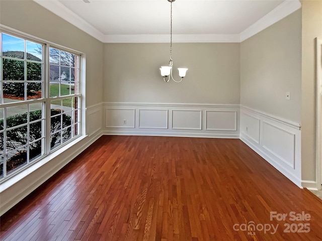 unfurnished dining area featuring crown molding, dark wood-style flooring, and an inviting chandelier