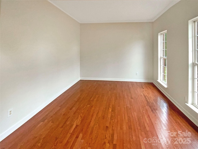 spare room featuring baseboards and wood finished floors