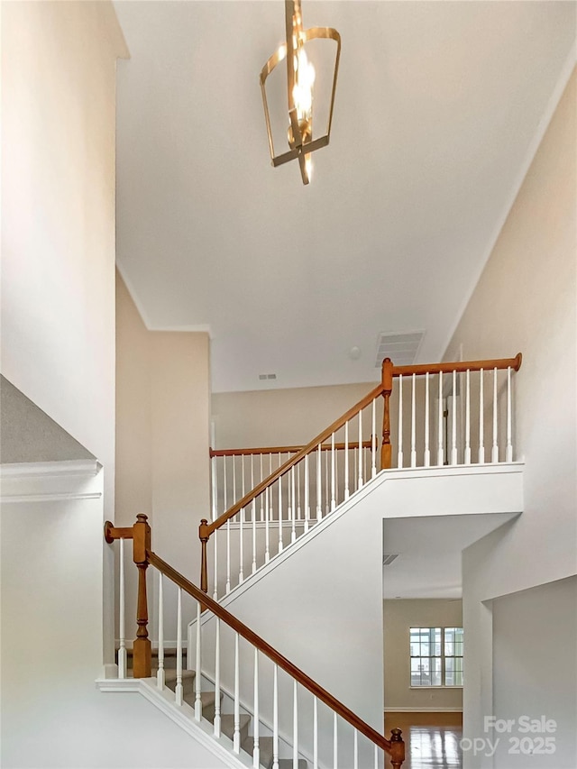 staircase with a chandelier, a high ceiling, and visible vents