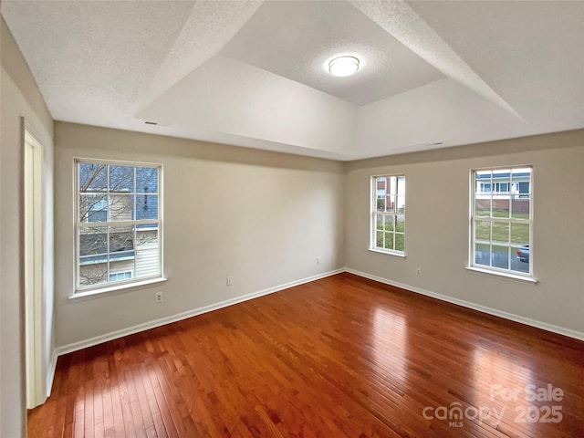 spare room featuring a textured ceiling, dark wood-style flooring, visible vents, and baseboards