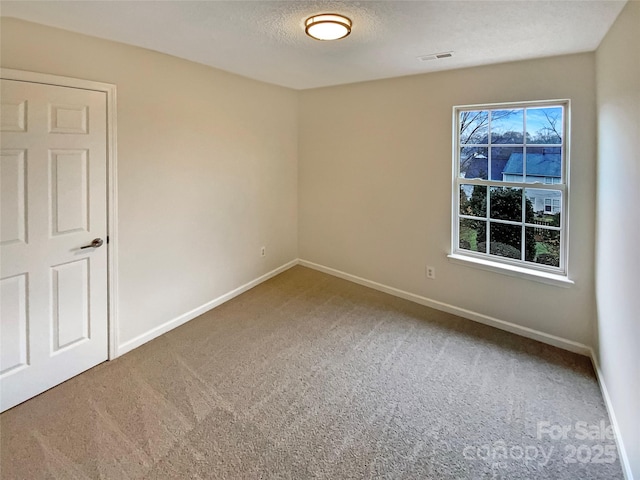 carpeted empty room with baseboards, visible vents, and a textured ceiling