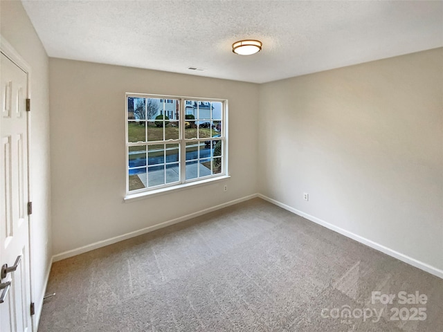 empty room with carpet floors, visible vents, baseboards, and a textured ceiling