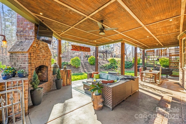 view of patio / terrace with ceiling fan and an outdoor living space with a fireplace