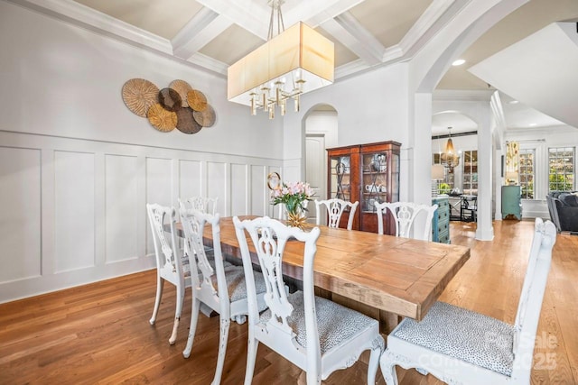 dining space featuring beam ceiling, wood-type flooring, a chandelier, crown molding, and coffered ceiling