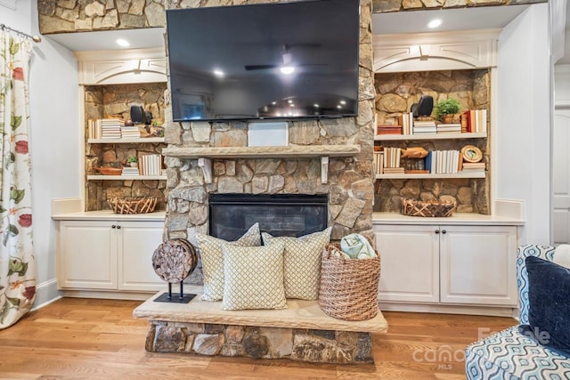 living room featuring light hardwood / wood-style flooring and a stone fireplace