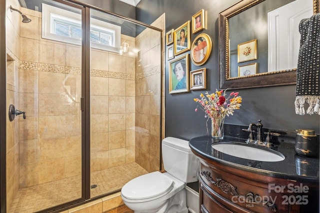 bathroom featuring toilet, a shower with door, and vanity