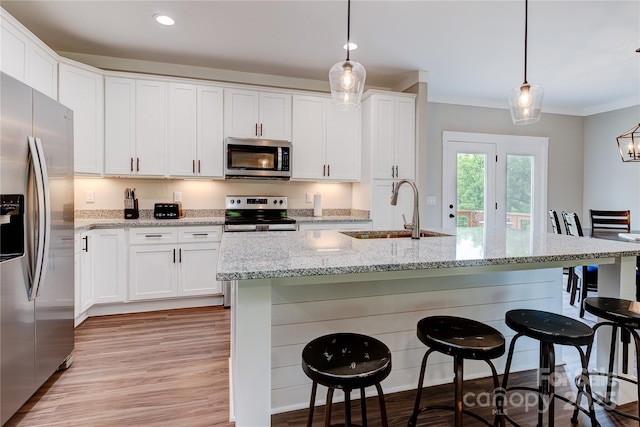 kitchen featuring stainless steel appliances, a breakfast bar, a sink, white cabinetry, and light wood-type flooring