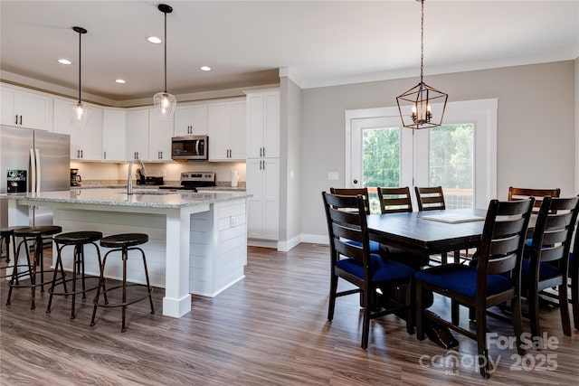 dining space featuring a chandelier, recessed lighting, baseboards, dark wood finished floors, and crown molding