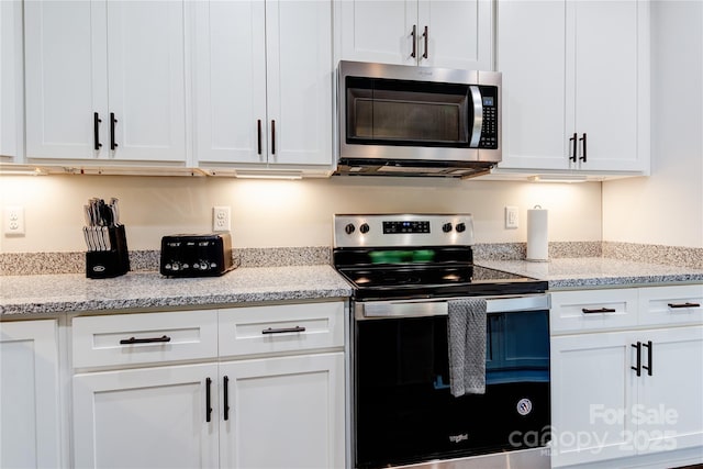 kitchen with stainless steel appliances, light stone countertops, and white cabinets