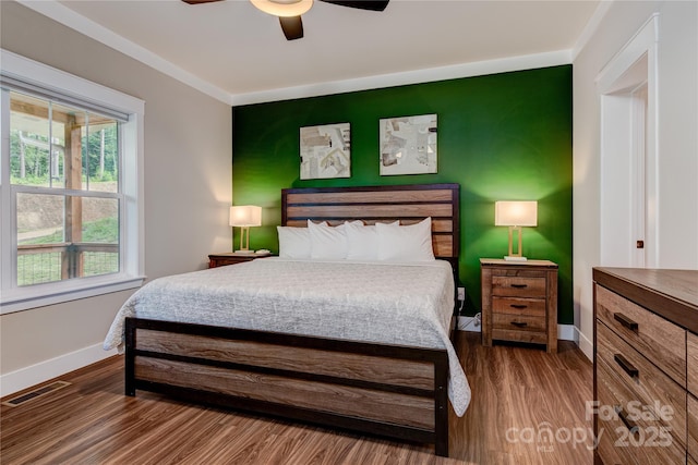 bedroom with a ceiling fan, visible vents, baseboards, and wood finished floors