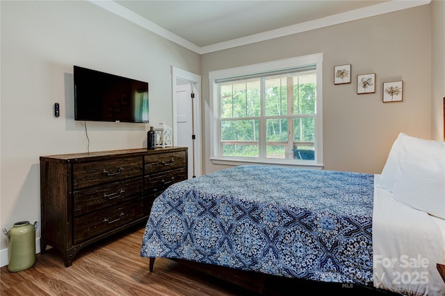 bedroom with ornamental molding and wood finished floors