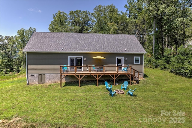 back of house with a shingled roof, an outdoor fire pit, a lawn, and a deck