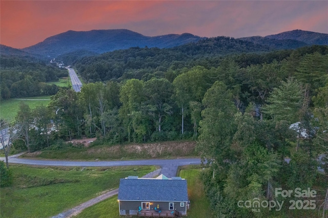 aerial view at dusk featuring a mountain view and a forest view