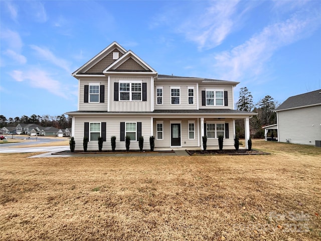 view of front of house featuring a porch, a front lawn, and board and batten siding