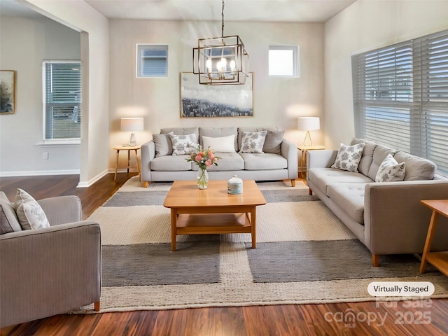 living area featuring dark wood-style floors, baseboards, and an inviting chandelier