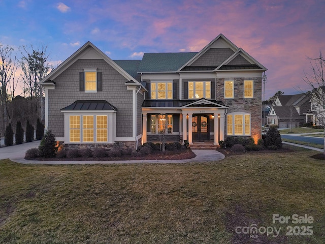 view of front of property featuring french doors, stone siding, a front yard, and a standing seam roof