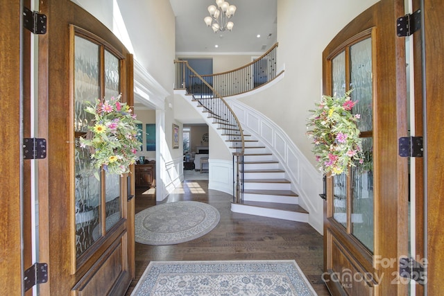 entrance foyer with stairway, a high ceiling, an inviting chandelier, and wood finished floors