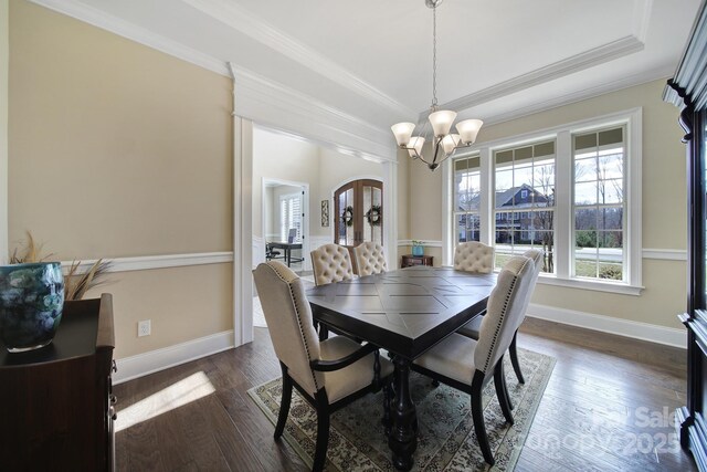 dining space featuring baseboards, dark wood-type flooring, an inviting chandelier, and ornamental molding