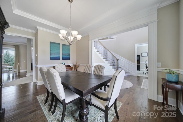 dining space featuring dark wood finished floors, ornamental molding, stairs, a raised ceiling, and a notable chandelier