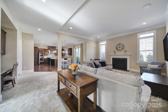 living room with a fireplace with flush hearth, recessed lighting, baseboards, and ornamental molding