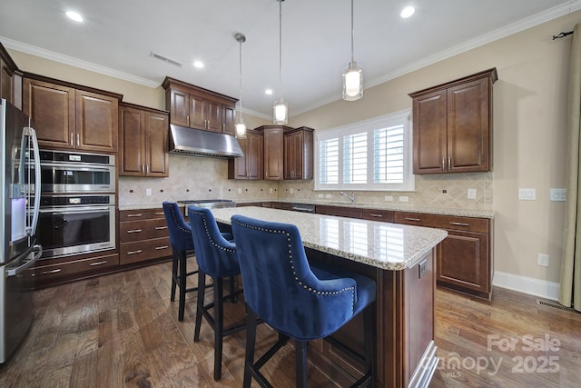 kitchen featuring under cabinet range hood, a center island, crown molding, and dark wood-style flooring