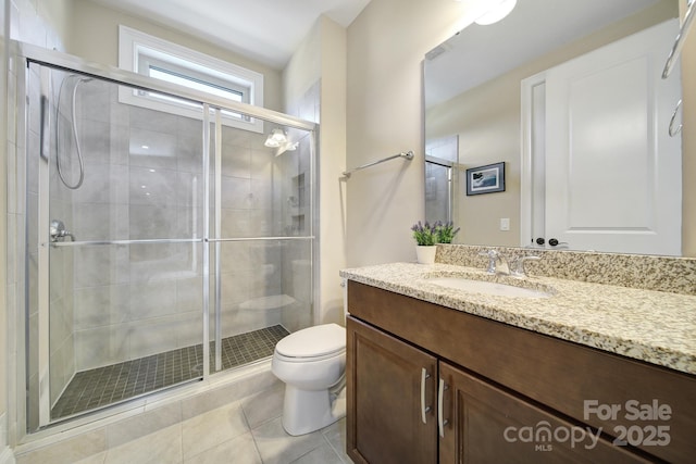 bathroom featuring tile patterned floors, a stall shower, toilet, and vanity