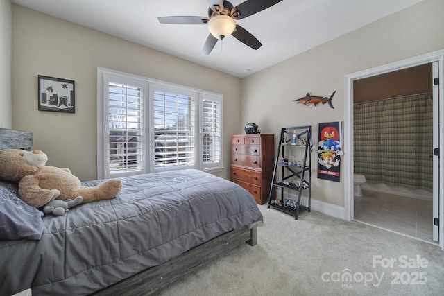 carpeted bedroom featuring baseboards, ensuite bath, and a ceiling fan