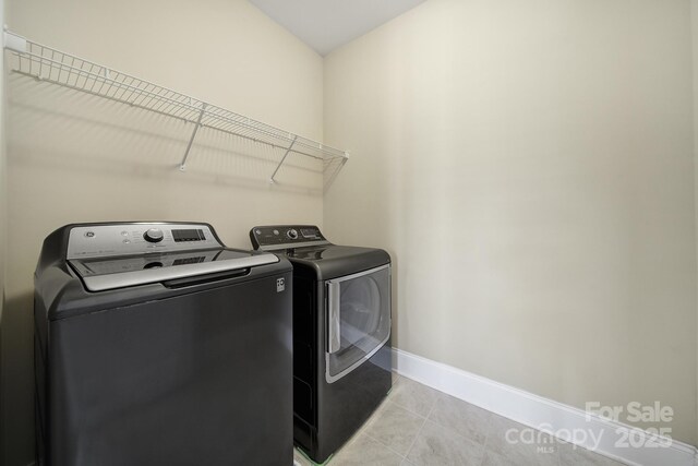 washroom with laundry area, light tile patterned floors, baseboards, and washer and clothes dryer