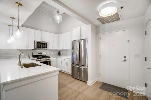 kitchen with decorative light fixtures, sink, stainless steel appliances, and white cabinetry