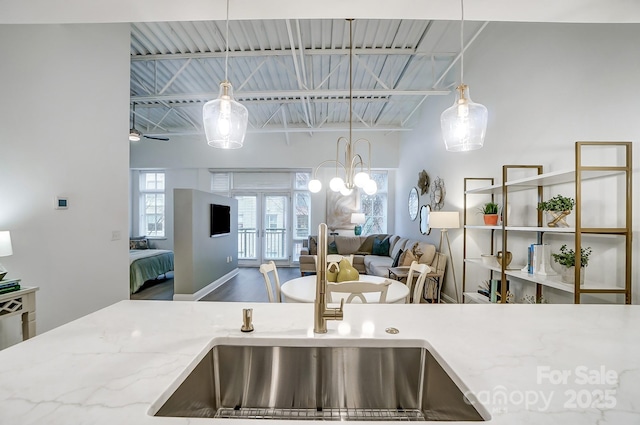 kitchen featuring french doors, light stone countertops, beamed ceiling, and decorative light fixtures