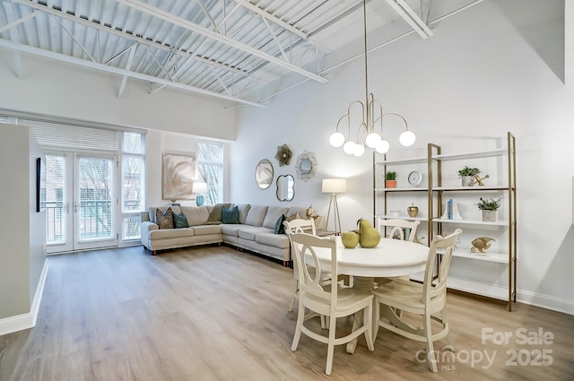 dining area with a high ceiling, french doors, and wood-type flooring