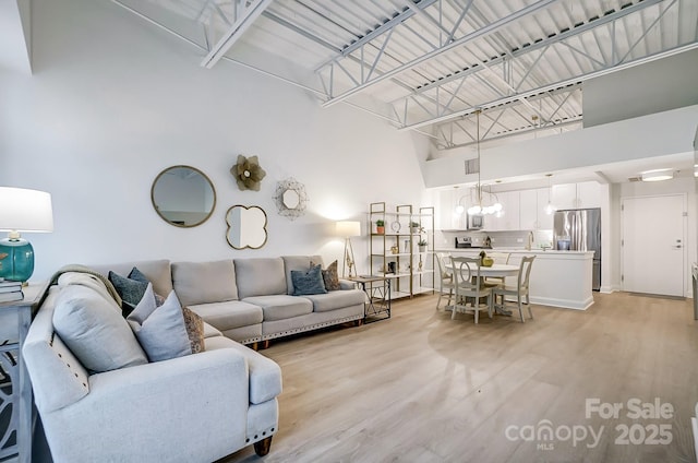 living room with light wood-type flooring and a high ceiling