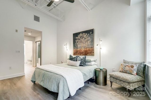 bedroom with hardwood / wood-style flooring, ceiling fan, a high ceiling, and ensuite bathroom