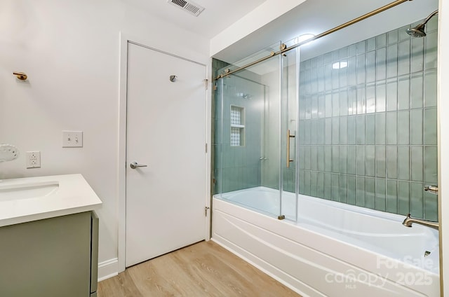 bathroom with hardwood / wood-style flooring, enclosed tub / shower combo, and vanity