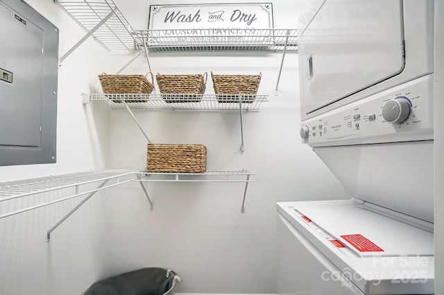 interior space with electric panel and stacked washer and dryer