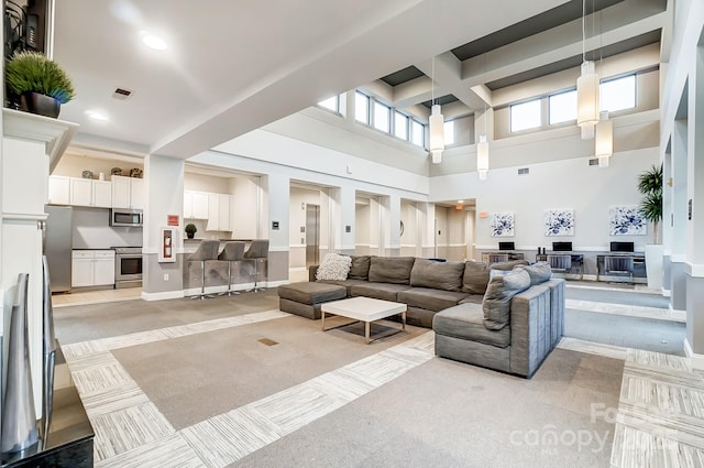 living room with beam ceiling, light carpet, and a towering ceiling