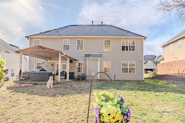 rear view of house featuring a hot tub, a lawn, fence, a patio area, and outdoor lounge area