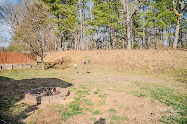 view of yard featuring an outdoor fire pit and fence