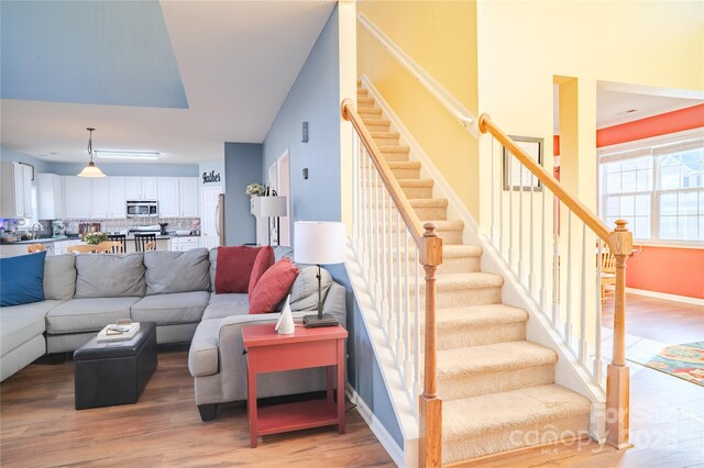 living area with baseboards, stairway, and light wood finished floors