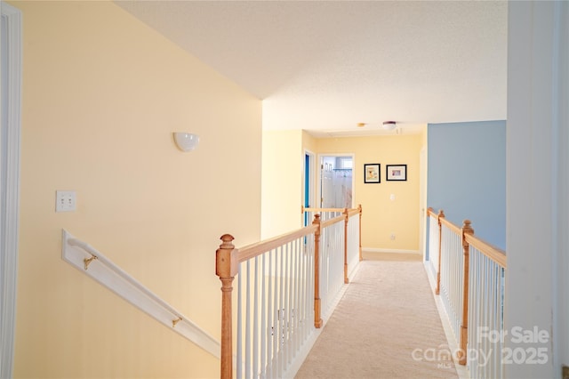 hallway featuring baseboards, light colored carpet, and an upstairs landing