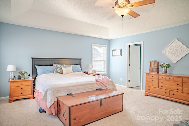 carpeted bedroom with baseboards, a tray ceiling, ceiling fan, and a textured ceiling