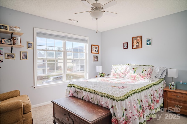 bedroom with ceiling fan, a textured ceiling, light colored carpet, visible vents, and baseboards