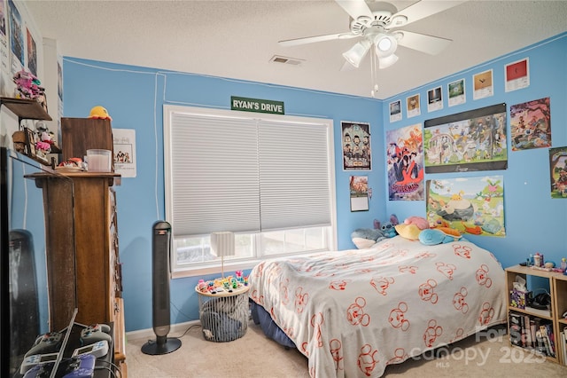 carpeted bedroom with a textured ceiling, ceiling fan, visible vents, and baseboards