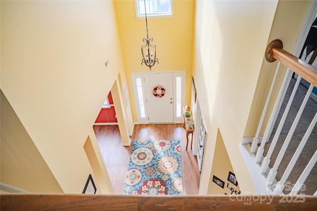 entrance foyer with a towering ceiling, stairway, a chandelier, and wood finished floors