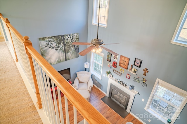 stairs featuring a fireplace with flush hearth, a high ceiling, and wood finished floors