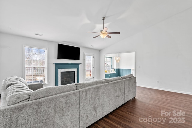 living room featuring lofted ceiling, dark wood-type flooring, a premium fireplace, and a healthy amount of sunlight