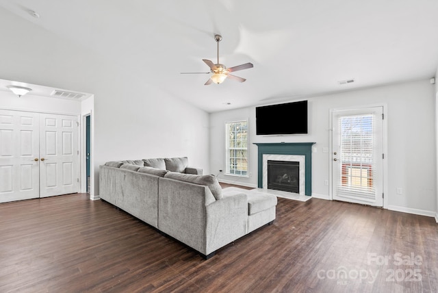 living room featuring a fireplace, dark wood-type flooring, and a healthy amount of sunlight