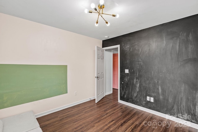 spare room with dark hardwood / wood-style floors and a chandelier